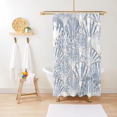 a shower curtain with shells on it in a white and blue bathroom, next to a bathtub