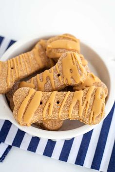 peanut butter dog treats in a white bowl on a blue and white striped tablecloth