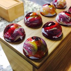 marbles are sitting on a wooden table with red, yellow and white swirled designs