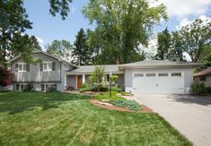 a large house with lots of grass in the front yard and trees on both sides