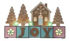 a gingerbread house with christmas trees and lights on it's front is the word joy