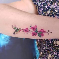 a woman's arm with pink flowers and hummings on the left side of her arm