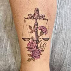 a woman's leg with a tattoo on it that has a scale and flowers on it