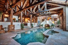 an indoor swimming pool in the middle of a large room with wooden beams on the ceiling