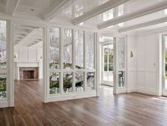 an empty living room with wood floors and white paint on the walls, windows, and doors