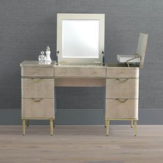 a desk with two drawers and a mirror on it in front of a gray wall