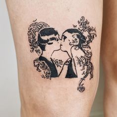 a couple kissing each other on the side of a woman's thigh with an artistic tattoo design