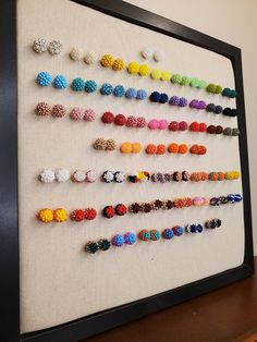 there are many different colored beads on the wall behind this framed art piece, which is made out of canvases