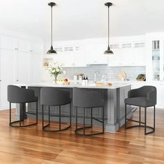 a kitchen with white cabinets and gray bar stools next to an island in the middle