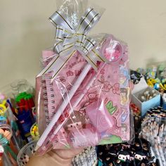 a person holding up a bunch of pens and notebooks in their hand, with other items on the table behind them