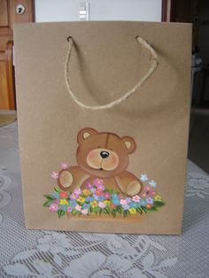 a brown paper bag with a teddy bear on the front and flowers in the back