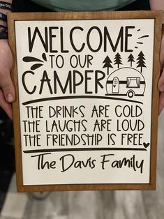 a person holding a sign that says welcome to our camper the drinks are cold and the laughs are loud