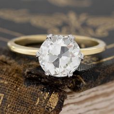 an old mine cut diamond sits on top of a book with gold trimmings