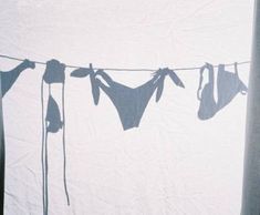 clothes hanging on a line in front of a white wall with the shadow of an elephant