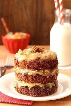 a stack of cake sitting on top of a white plate next to a glass of milk