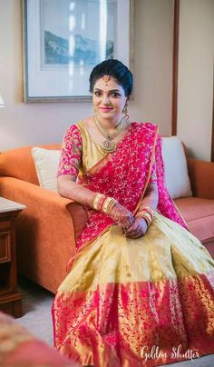 a woman sitting on top of a couch wearing a pink and yellow sari dress