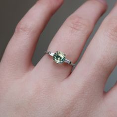 a person's hand with a ring on it and a green stone in the middle