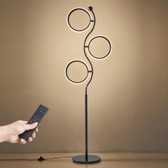 a person holding a remote control in front of a lamp that has circles on it