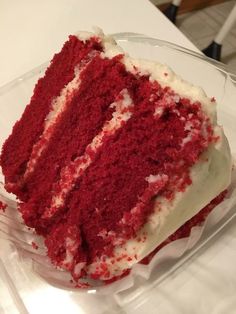 a slice of red velvet cake sitting on top of a glass plate with white frosting