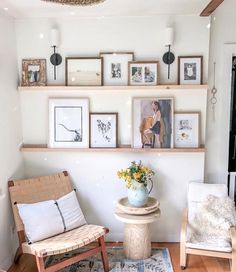 a living room filled with furniture and framed pictures on the wall above a small table