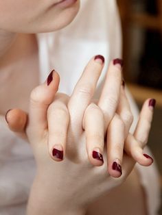 a woman with red nail polish holding her hands together