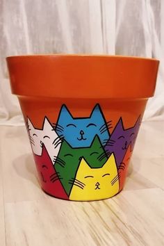 an orange flower pot with cats painted on it