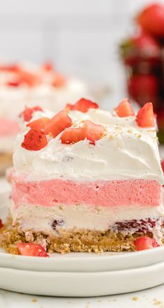 a slice of strawberry cream cake on a plate with strawberries in the background and another piece missing