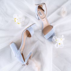 a pair of blue high heeled shoes sitting on top of a white bed sheet