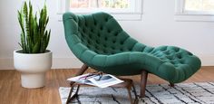 a green chair sitting on top of a rug next to a potted plant