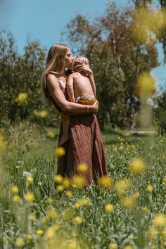 a man and woman standing in the middle of a field with yellow flowers on it