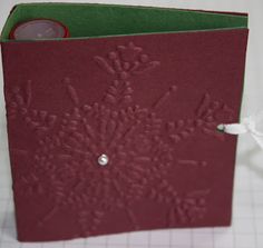 a close up of a red card with a white string attached to it and a button in the middle