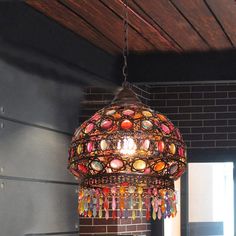 a chandelier hanging from the ceiling in a room with brick walls and wooden beams