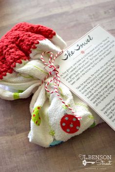 an open book with a red and white knitted hat next to it on a wooden floor