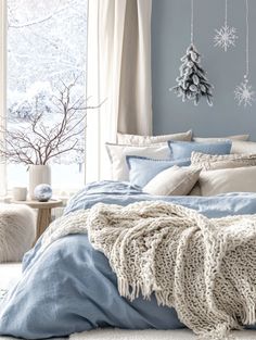 a bedroom with blue walls and white bedding in the corner, snowflakes hanging on the wall