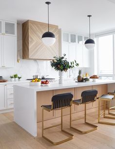 a kitchen with white cabinets and black chairs next to an island in the middle of the room