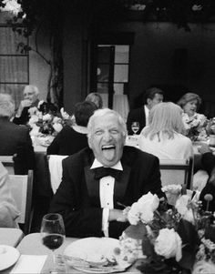 an old man in a tuxedo at a dinner table with his mouth open