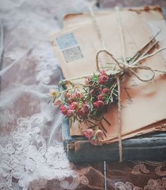 an old book with flowers tied to it on a lace tablecloth covered bed spread