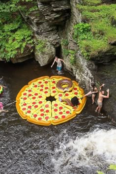 people are playing in the water near a giant pizza float that is floating on top of a river