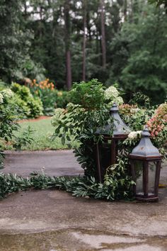 an old fashioned lamp surrounded by flowers and greenery