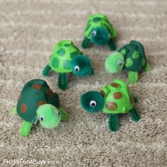 several green and brown stuffed animals laying on the floor with their faces painted to look like turtles