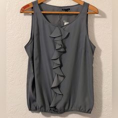 Women’s Sleeveless Blouse From Gap. Nwt Xxl But Fits More Like And Xl. Would Look Great Under A Blazer. Ruffles Down The Front And Elastic On The Bottom Armpit To Armpit 23” Length 26” Gray Spring Gap Cami Tops, Gap Ruffled Tops For Summer, Gap Spring Cami Tops, Gap Cami Tops For Spring, Summer Ruffled Tops By Gap, Summer Ruffled Tops From Gap, Elegant Sleeveless Gray Tops, Gap Sleeveless Tank Top For Summer, Gap Sleeveless Summer Camisole