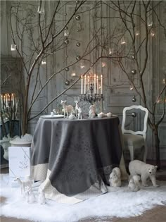 a dining room table covered in snow with candles and ornaments on the table, surrounded by trees