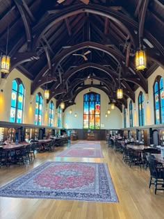 the inside of a large dining hall with tables, chairs and rugs on the floor