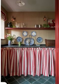 a red and white striped table cloth with blue plates on it in front of a shelf