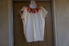 "An ethnic, summer festive blouse that is embellished with floral embroidery. Short sleeves. Medium - Large. Condition - has some spots - see photos. Measurements taken across front laid flat Bust24\" Shoulder to hem26\" Waist24\"" White Yoke Blouse For Summer, White Summer Top With Yoke Detail, Traditional Summer Blouse With Boho Collar, Traditional Summer Tops For Festive Occasions, Cotton Tops For Beach Festivals, Cotton Blouse With Embroidered Neckline For Festival, Traditional Blouse With Boho Collar For Summer, Folk Style Cotton Blouse For Fiesta, Folk Style Festive Tops For Summer