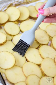 a person holding a brush on top of sliced potatoes