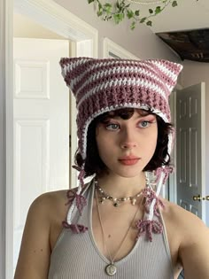 a woman wearing a knitted cat hat with beads on her neck and necklace around her neck