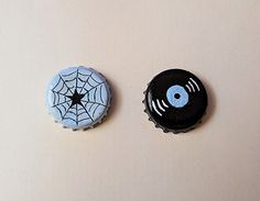 two bottle caps with designs on them sitting next to each other in front of a white background