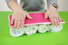 a woman holding a pink and white surfboard on top of a green countertop