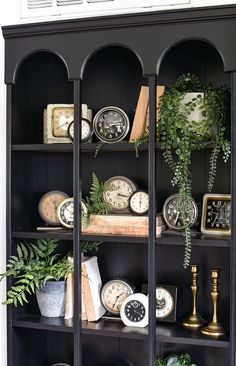 a black bookcase filled with lots of different types of clocks on top of it